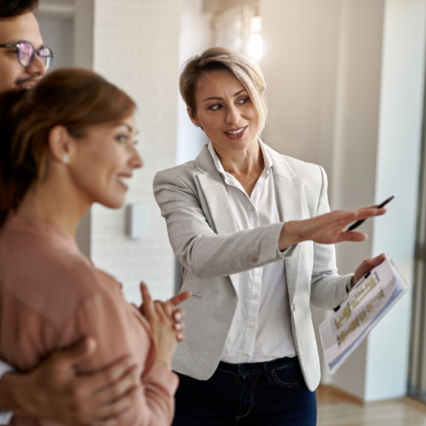 smiling-real-estate-agent-talking-with-couple-interested-buying-new-home